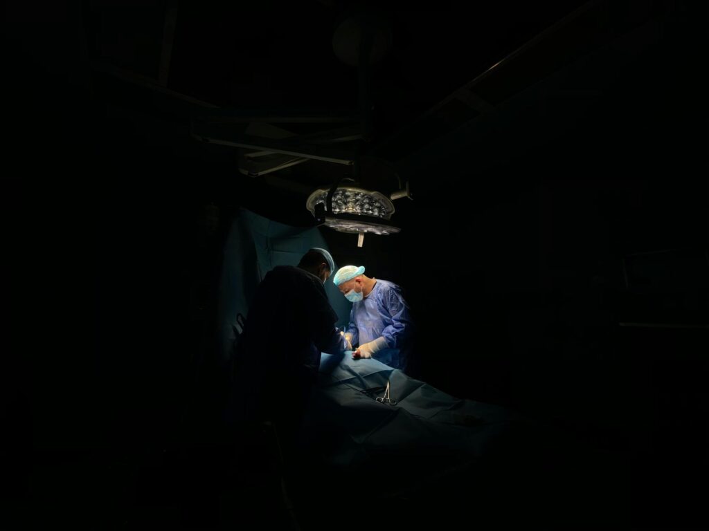 Two surgeons focus intently on a medical operation under surgical lights.