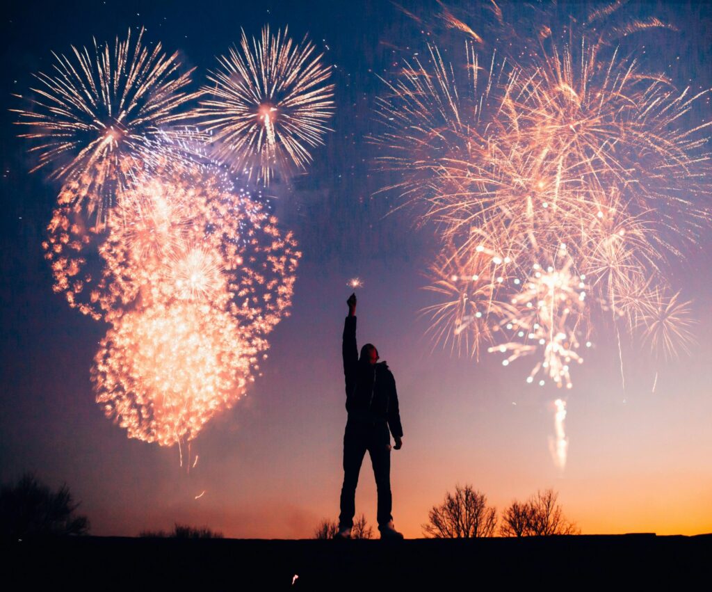 A person celebrates under vibrant fireworks in the evening sky in Kragujevac, Serbia.